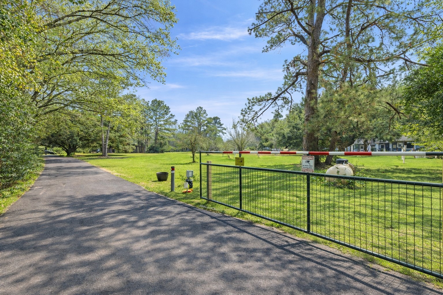 22625 Tomball Cemetery Road Tomball, TX 77377 - Photo 5 of 32 A scenic driveway lined with trees leads to a gated entrance, providing privacy. RV Cover complete with water, electrical hookup, and waste disposal hookup.