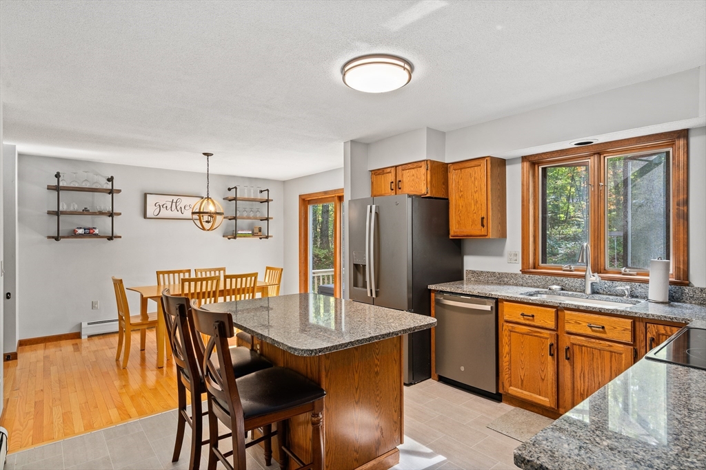 634 Burts Pit Road Northampton, MA 01062 - Photo 9 of 42 a dining hall with stainless steel appliances granite countertop a stove a refrigerator a sink dishwasher a dining table and chairs with wooden floor