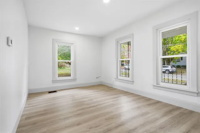a view of an empty room with a window and wooden floor