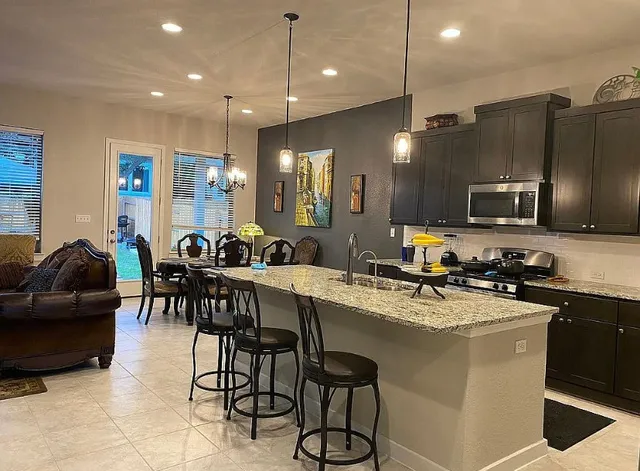 a kitchen with a sink stainless steel appliances and chairs