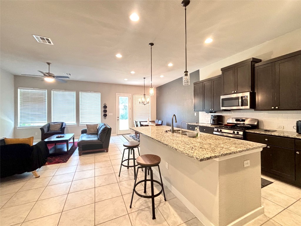 2017 Palmera Ridge Boulevard Leander, TX 78641 - Photo 17 of 17 a kitchen with stainless steel appliances kitchen island granite countertop a stove a sink a refrigerator a dining table and chairs with wooden floor