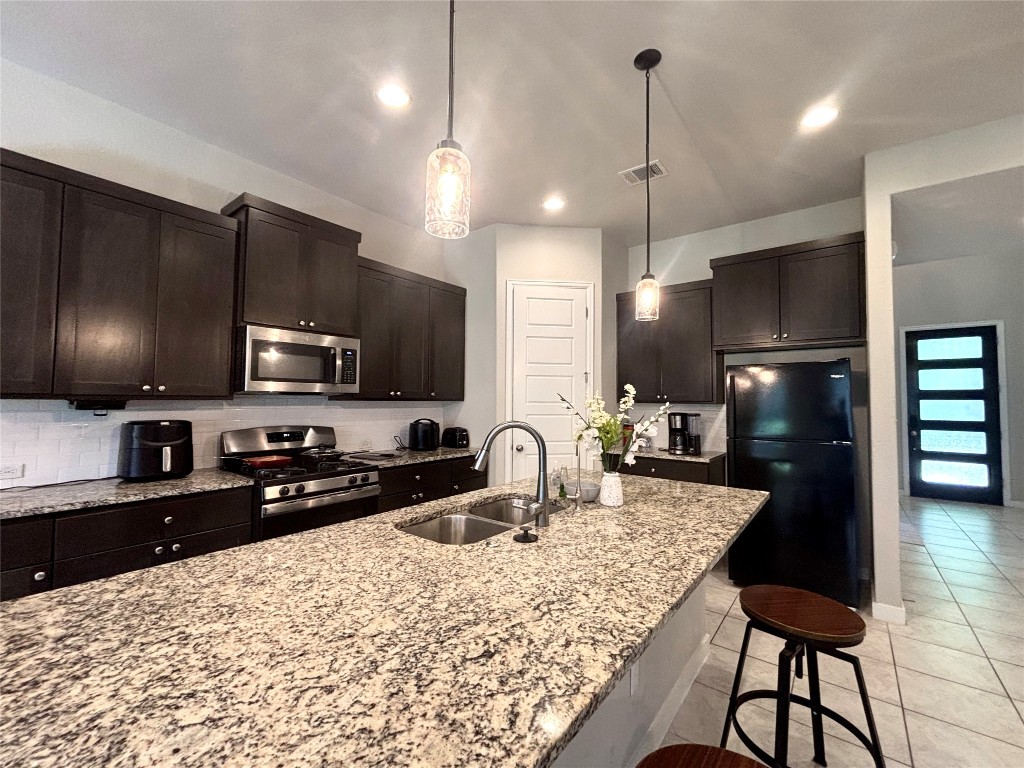 2017 Palmera Ridge Boulevard Leander, TX 78641 - Photo 9 of 17 a kitchen with stainless steel appliances kitchen island granite countertop a sink refrigerator and cabinets
