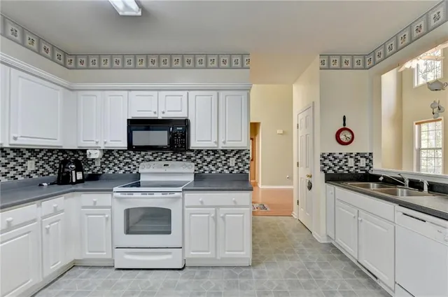 a kitchen with white cabinets and appliances