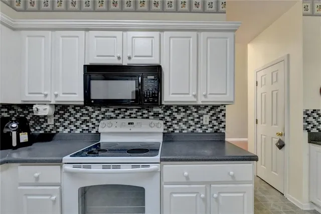 a kitchen with granite countertop white cabinets and black appliances