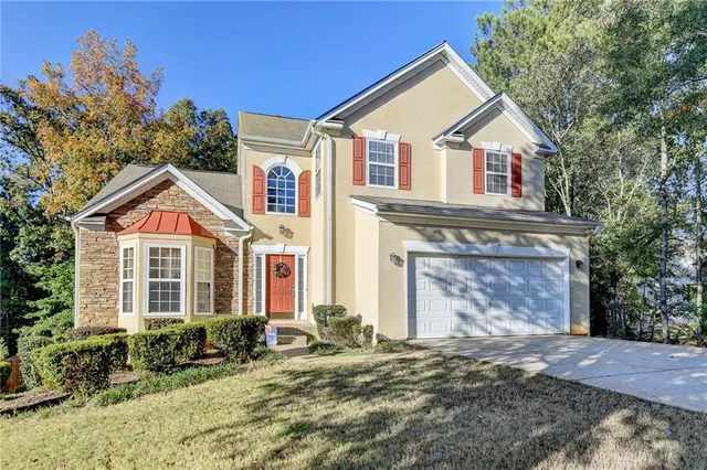 a view of a yard in front of a brick house with large windows