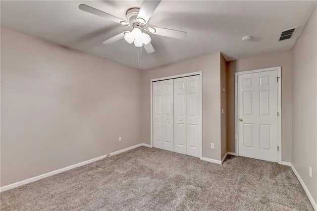 an empty room with a chandelier fan and windows