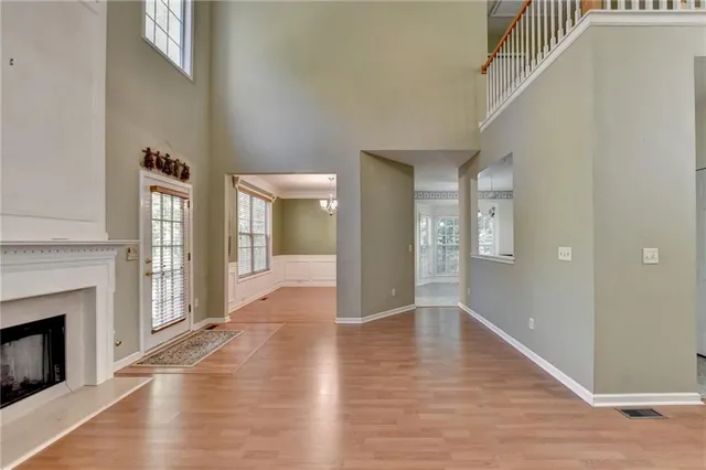 a view of an empty room with wooden floor and a fireplace