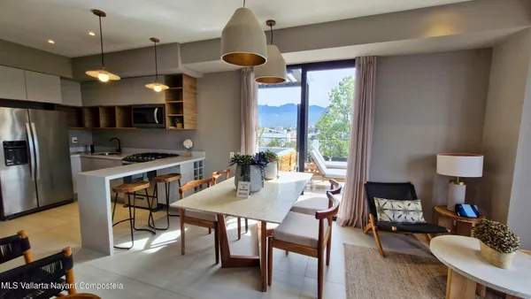 a kitchen with stainless steel appliances a stove a refrigerator a sink a dining table and chairs with wooden floor