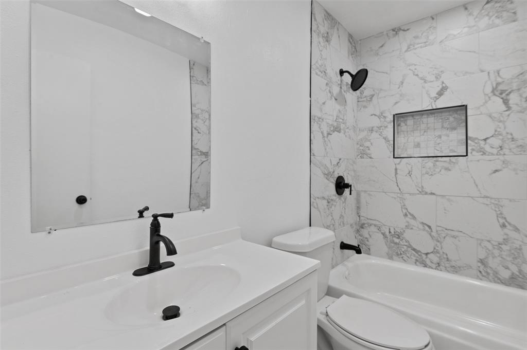 2068 East Peters Colony Road Carrollton, TX 75007 - Photo 14 of 24 a bathroom with a sink a toilet and a bathtub