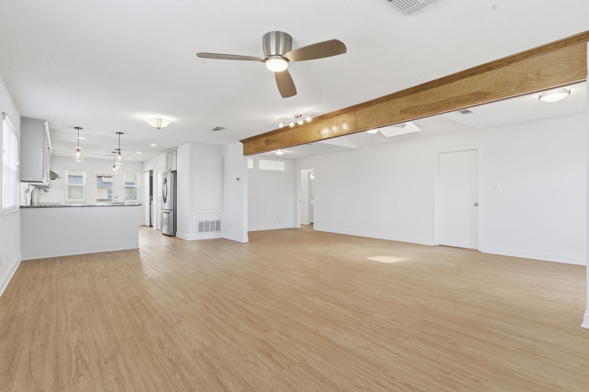 119 Sand Shoals Road Freeport, TX 77541 - Photo 17 of 34 Living room toward the kitchen — open sightline from the family room into the renovated kitchen, with brushed-nickel modern ceiling fan, exposed beam accent, and pass-through to the secondary bedrooms.