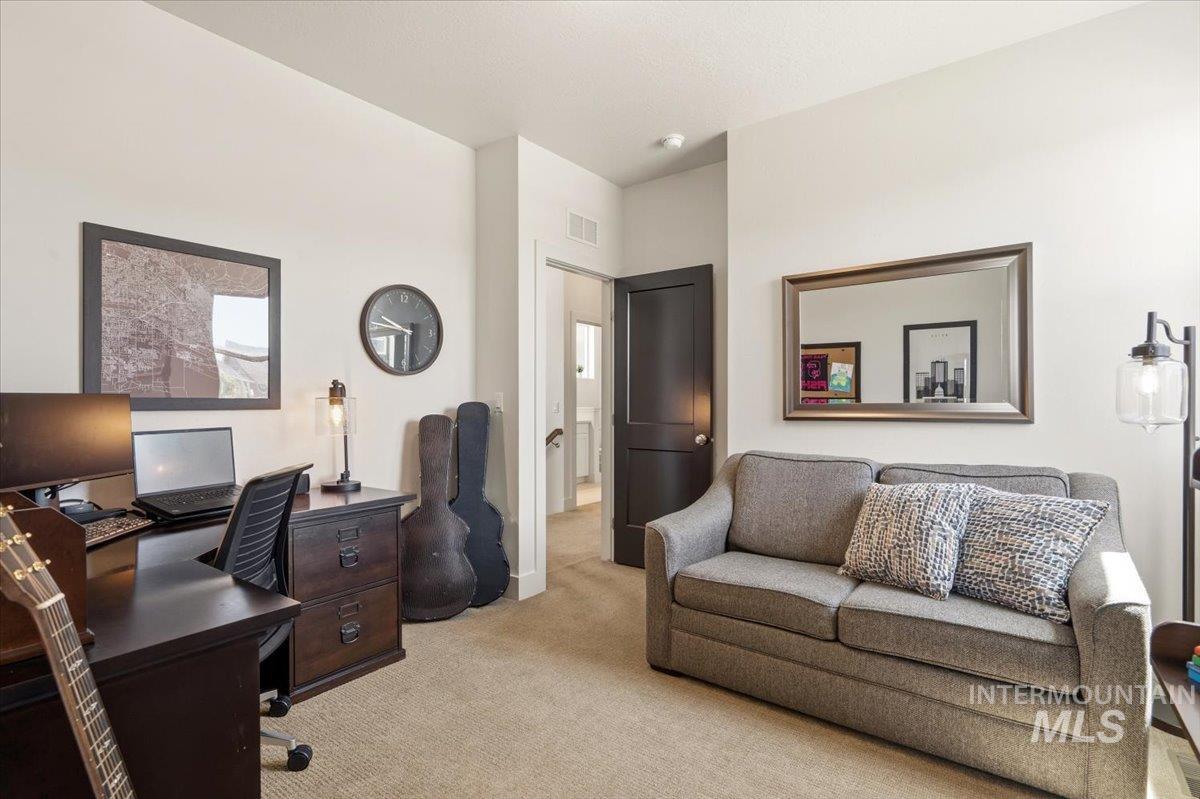 3794 South Single Tree Avenue Boise, ID 83716 - Photo 10 of 50 Neutral-toned carpeting enhances this versatile room, featuring a dark wood-finish desk with integrated drawers