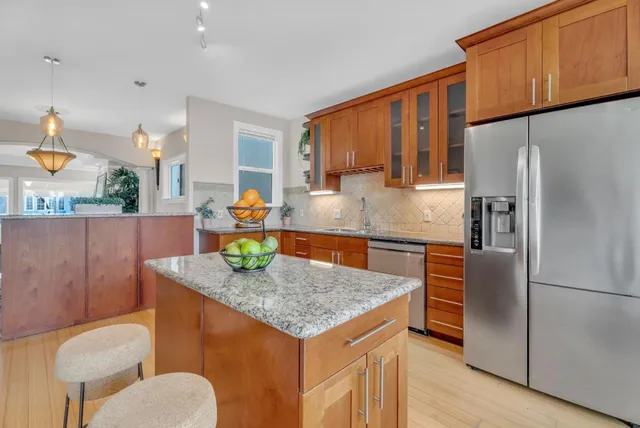 a living room with furniture kitchen view and a wooden floor