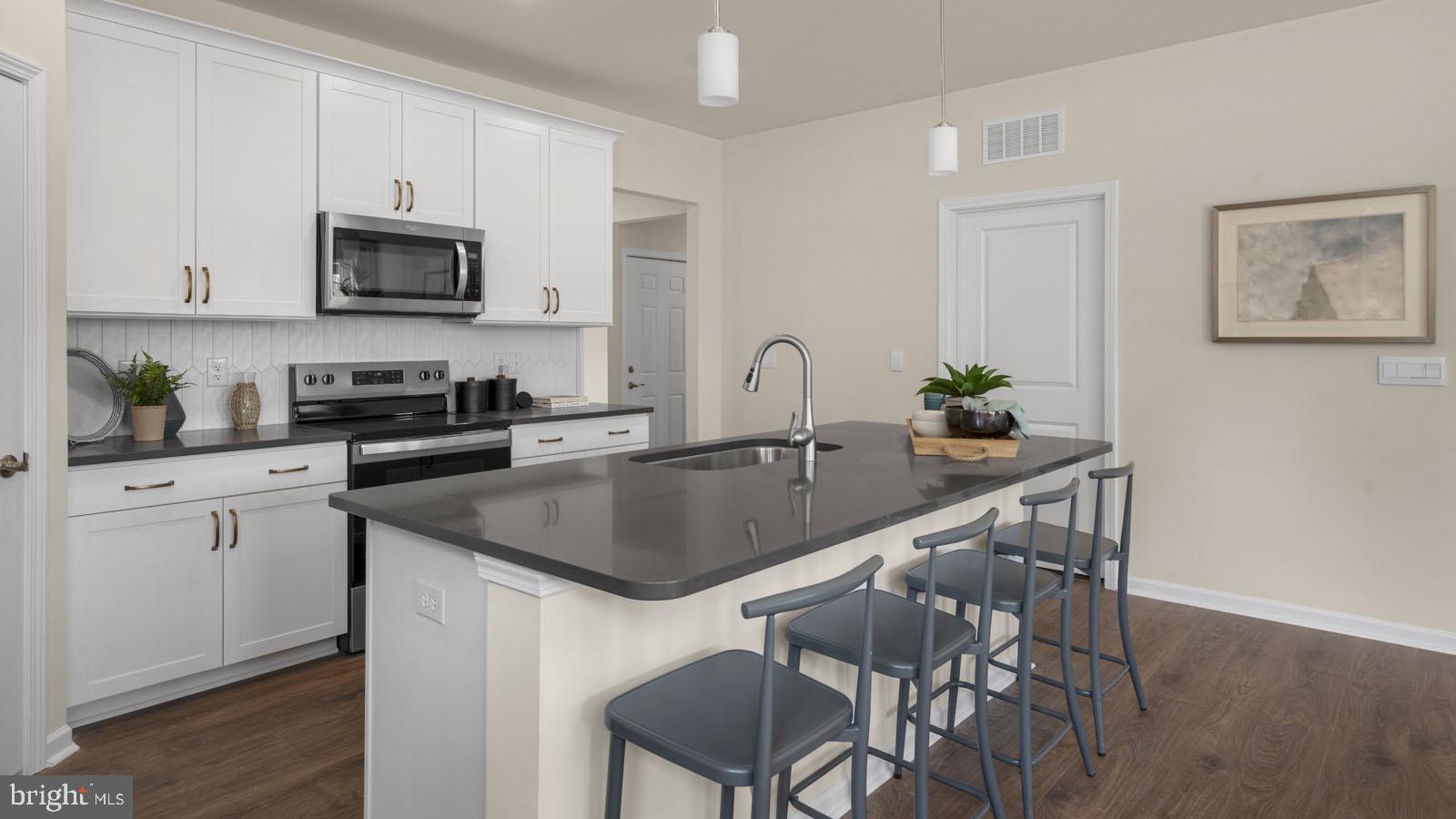 249 Hydrangea Way Winchester, VA 22602 - Photo 2 of 19 a kitchen with stainless steel appliances granite countertop a sink a microwave a stove and white cabinets