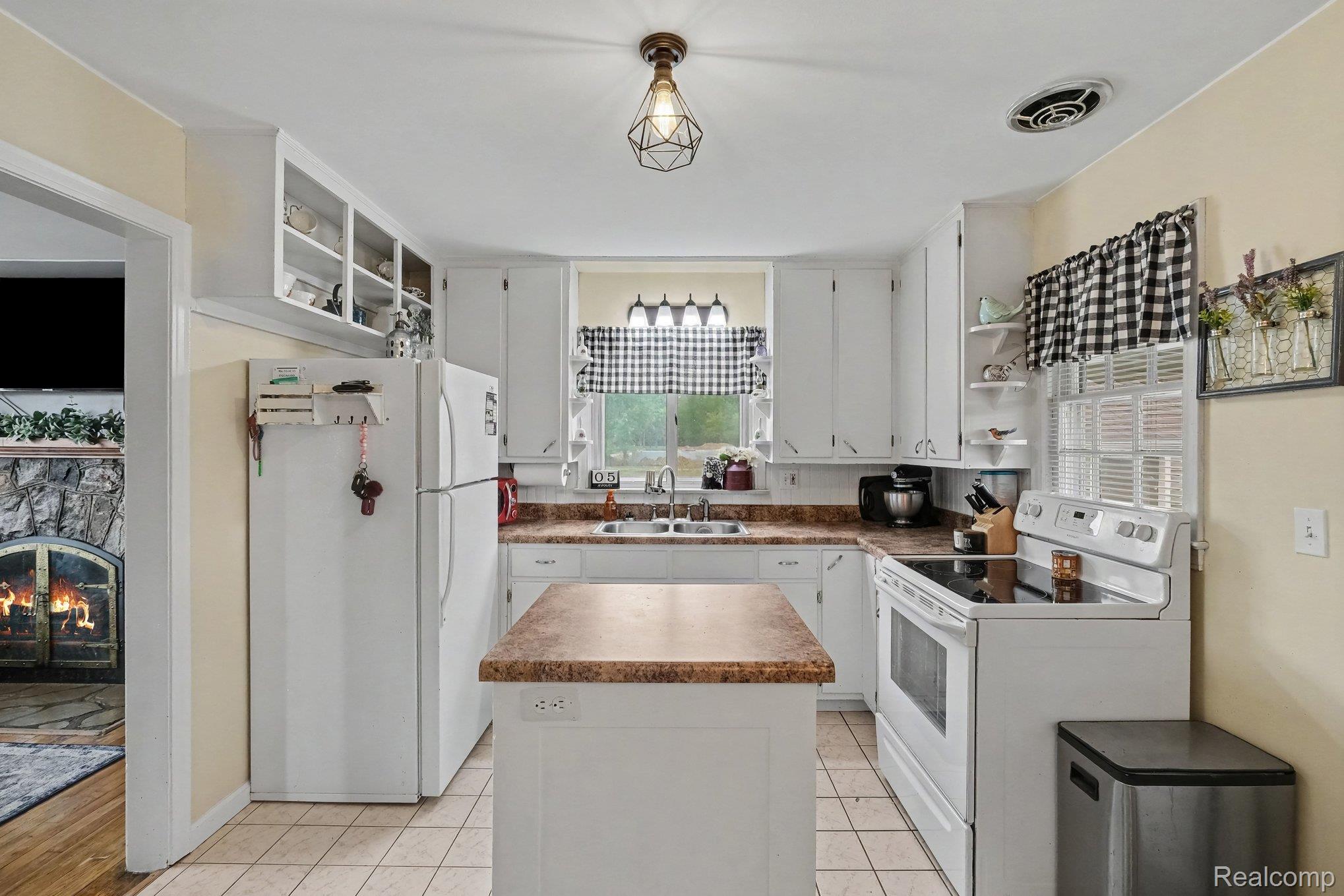 5409 Baldwin Road Swartz Creek, MI 48473 - Photo 6 of 27 White cabinetry, tile flooring, central kitchen island, light-toned countertops, and built-in shelving