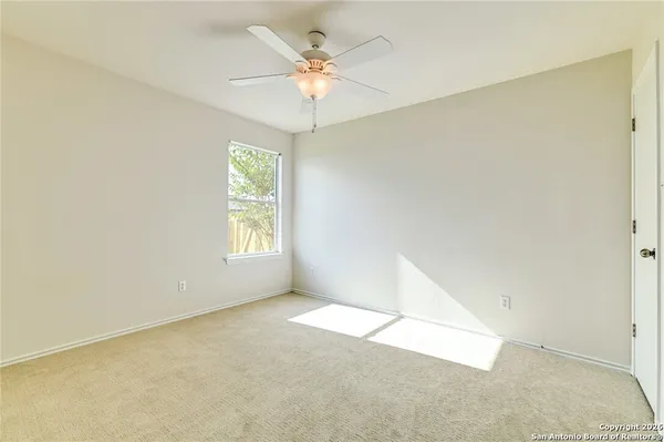an empty room with windows and chandelier fan