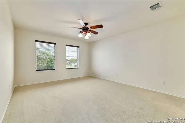 an empty room with windows and chandelier fan