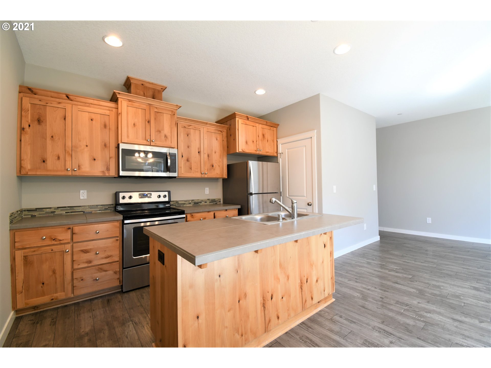 100 North 44th Place Ridgefield, WA 98642 - Photo 4 of 21 a kitchen with a sink a stove a microwave a center island and a window