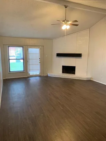 an empty room with wooden floor chandelier fan and windows