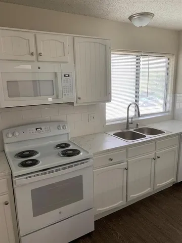a kitchen with cabinets appliances a sink and a window