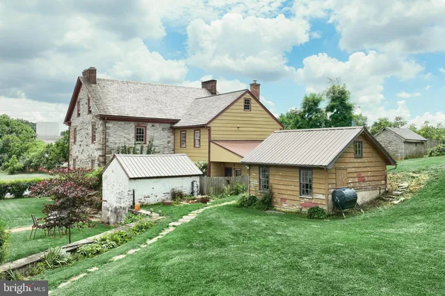 a aerial view of a white house sitting in big yard with large tree