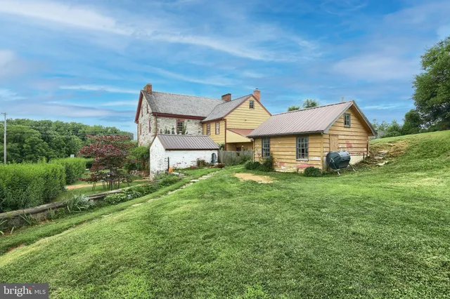 a view of a house with a big yard plants and large trees