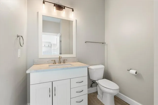a bathroom with a toilet sink vanity and mirror