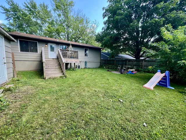 a backyard of a house with wooden fence and a large tree