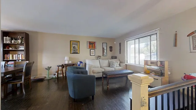 a living room with furniture a bookshelf and a window