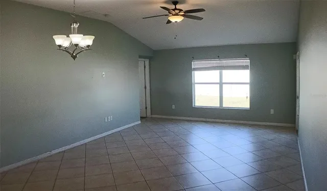 an empty room with a chandelier fan and windows