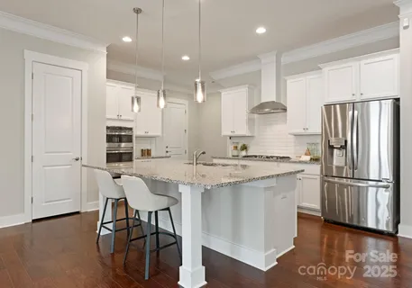 a kitchen with stainless steel appliances granite countertop a refrigerator a sink dishwasher a stove and a refrigerator with wooden floor