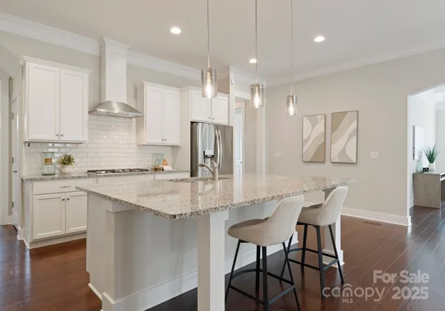 a kitchen with stainless steel appliances granite countertop a stove refrigerator sink and white cabinets
