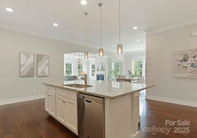 a kitchen with stainless steel appliances granite countertop a sink a oven a dining table and chairs with wooden floor
