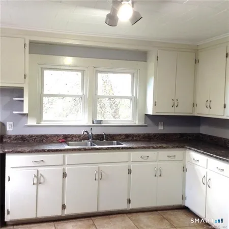 a kitchen with granite countertop white cabinets white appliances and a wide window