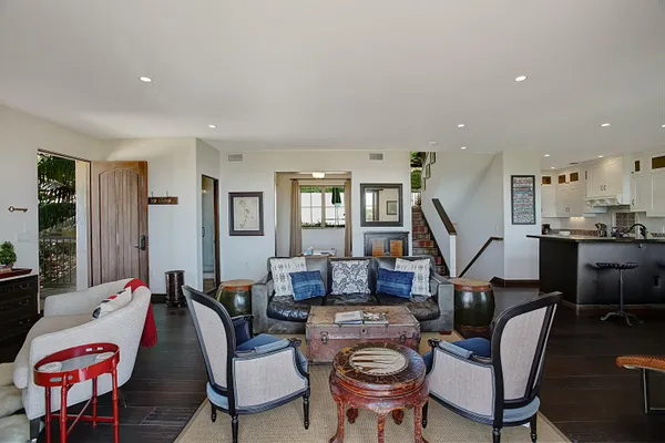 a living room with furniture kitchen view and a wooden floor