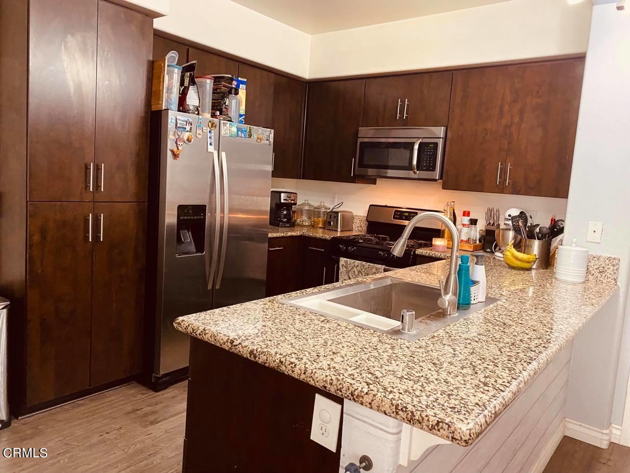 a kitchen with stainless steel appliances granite countertop a sink refrigerator and microwave