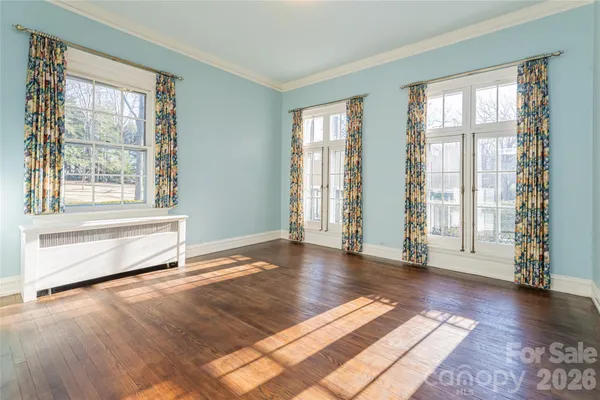 a view of an empty room with window and wooden floor