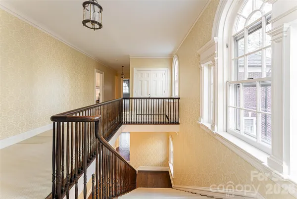 a view of a hallway with wooden floor and windows