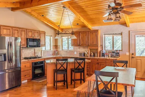 a kitchen with stainless steel appliances granite countertop a stove top oven a refrigerator a dining table and chairs with wooden floor