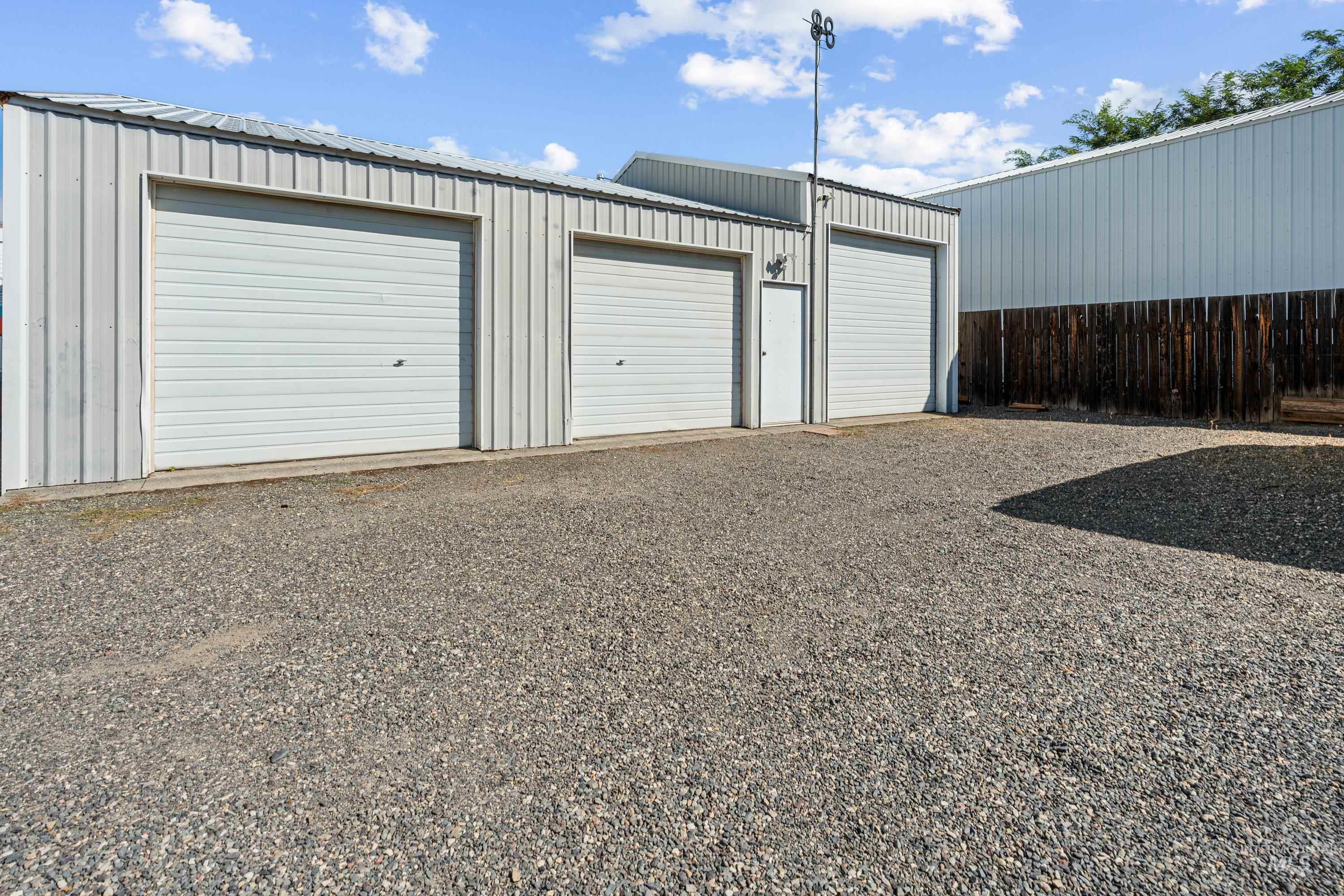 1266 Maple Street Clarkston, WA 99403 - Photo 32 of 44 Three white roll-up garage doors with exterior light fixture