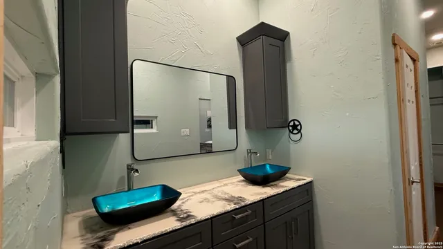 a bathroom with a granite countertop sink and a mirror