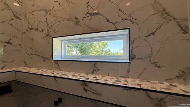 a bathroom with a granite countertop sink and a window