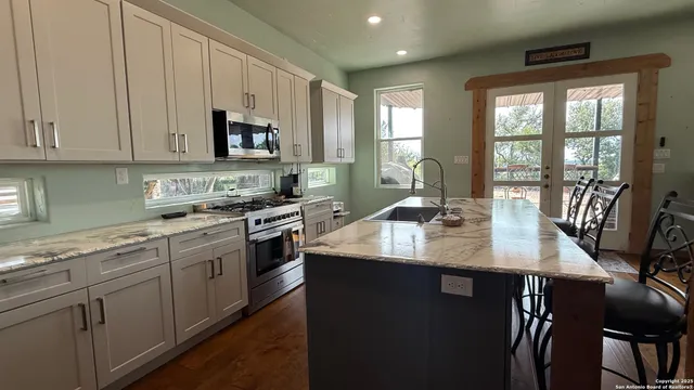 a kitchen with stainless steel appliances granite countertop a sink a stove and white cabinets
