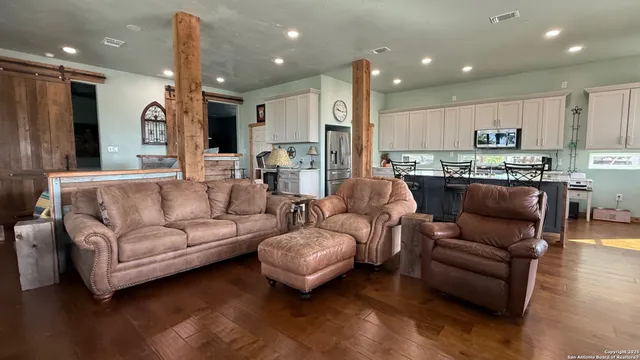 a living room with furniture kitchen area and a wooden floor