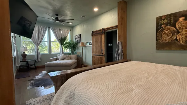 a bedroom with a bed a couch and a flat tv screen