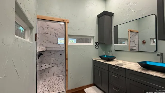 a bathroom with a granite countertop sink mirror and shower