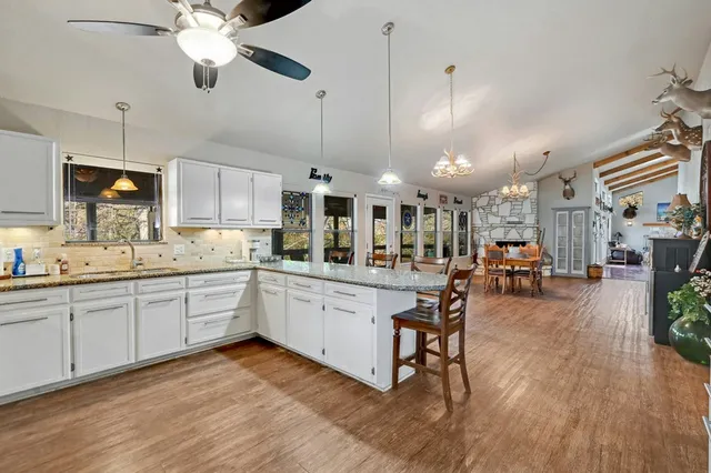 a kitchen with stainless steel appliances kitchen island hardwood floor sink stove dining table and chairs