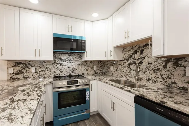 a kitchen with granite countertop white cabinets and stainless steel appliances