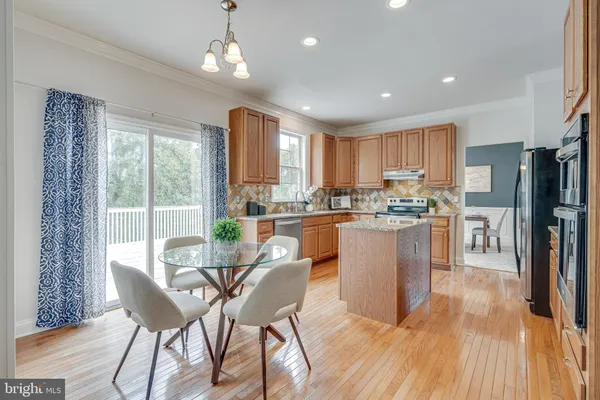 a kitchen with a sink a refrigerator a stove and chairs with wooden floor