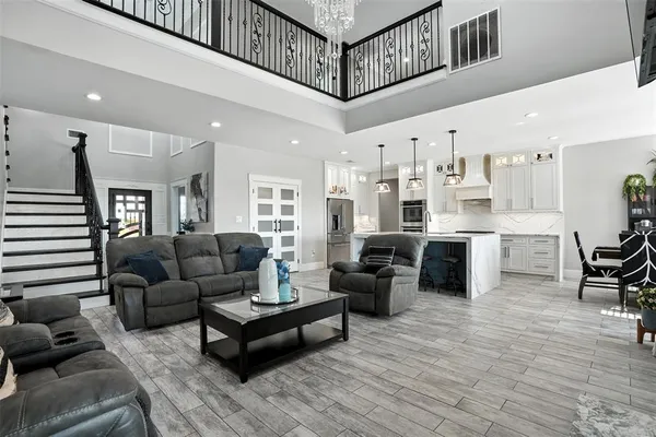 a living room with furniture a kitchen view and a chandelier