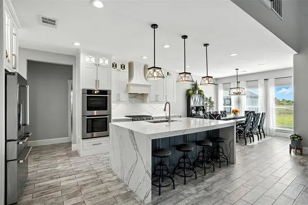 a kitchen with stainless steel appliances kitchen island granite countertop a table chairs and a stove